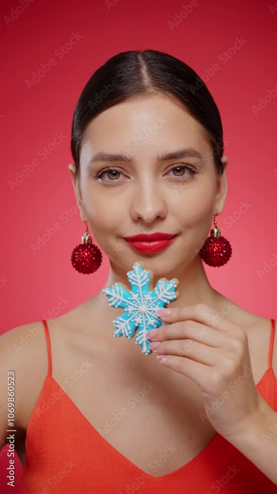 Beautiful young woman with a snowflake made of cookies, isolated on red background. Christmas or New Year festivities. Holiday and Party. Slow motion vertical video
