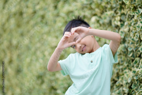 Cute boy makes a heart shape with his hands through his eyes. Children have emotions of love..Children have emotions of love.