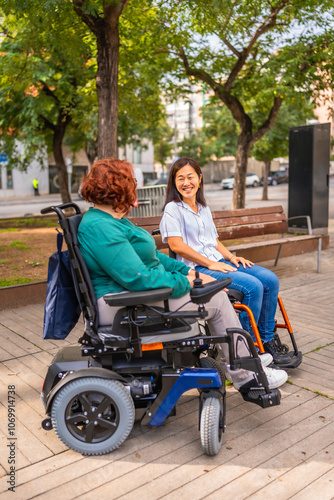 Women with disabilities in wheelchair talking relaxed in a park