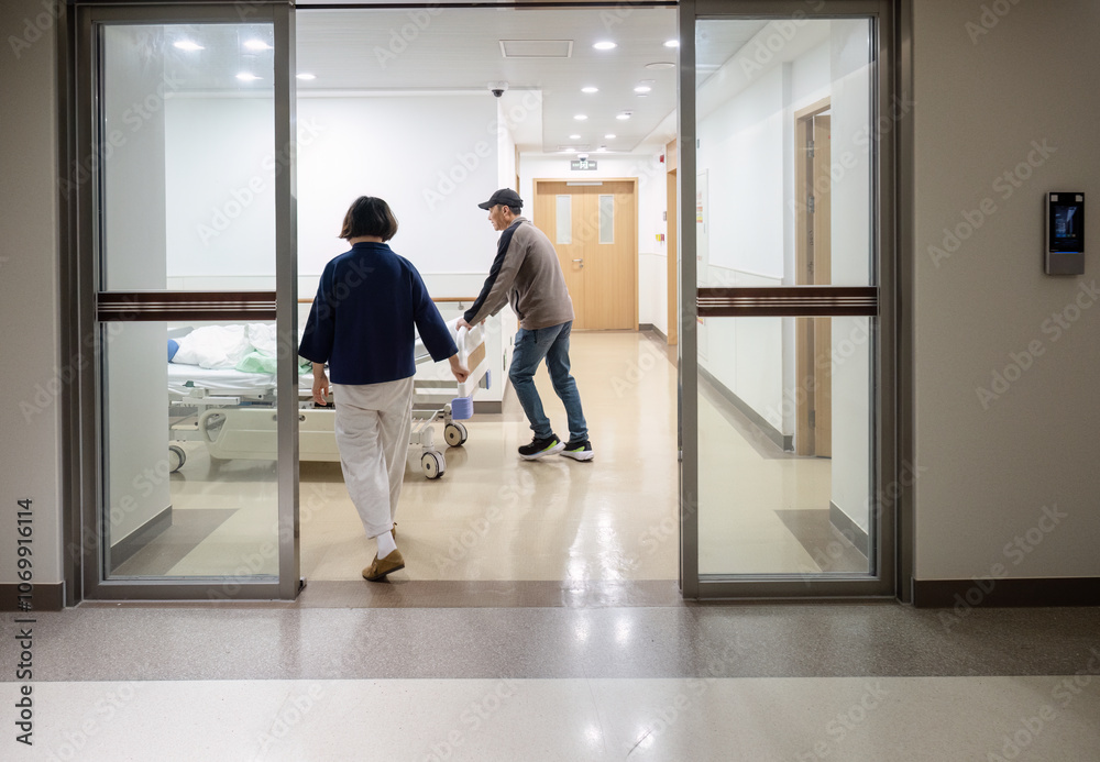Family members helping to push patient lying in bed in a corridor at the hospital.