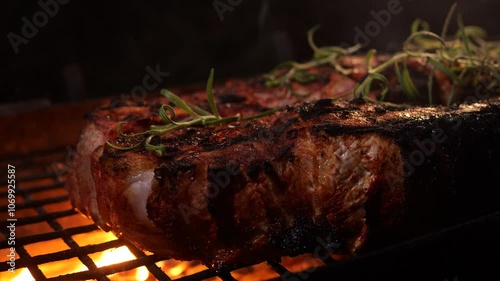 Meat being grilled on barbecue grill. juicy meat on grill over an open fire with herbs and rosemary