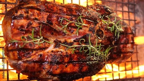 Juicy large piece of meat with branch of rosemary and spices is grilled. Picnic party with barbecue in nature in evening. dinner is being prepared on coals and fire