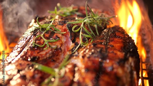 Juicy large piece of meat with branch of rosemary and spices is grilled. Picnic party with barbecue in nature in evening. dinner is being prepared on coals and fire