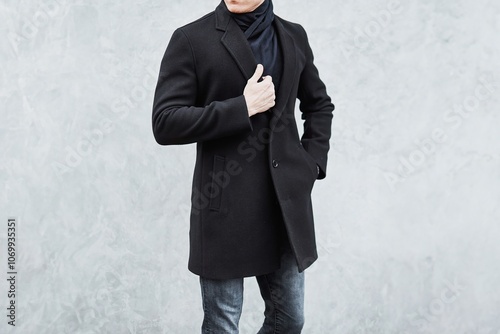 Foto Fashionable man wearing black coat and jeans in urban setting