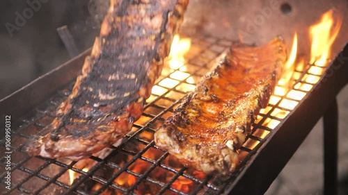 Barbecue grill. person turns over Grilled BBQ ribs Cooked on coals with tongs for summer and spring barbecue parties outdoors. Juicy barbecue ribs cooked on smoky grill