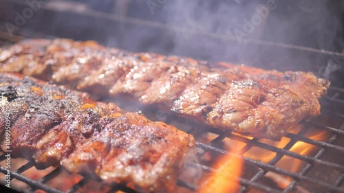 Barbecue grill. person turns over Grilled BBQ ribs Cooked on coals with tongs for summer and spring barbecue parties outdoors. Juicy barbecue ribs cooked on smoky grill