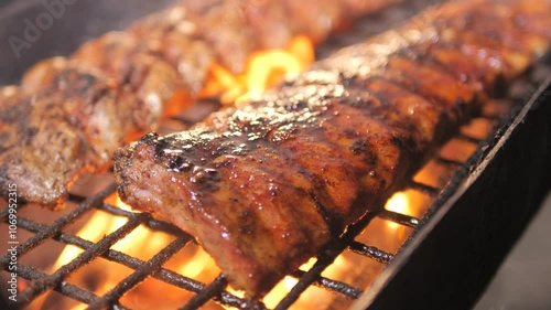 Barbecue grill. chef coats grilled BBQ ribs cooked on coals with sauce for summer and spring barbecue parties outdoors. Juicy barbecue ribs cooked on smoky grill