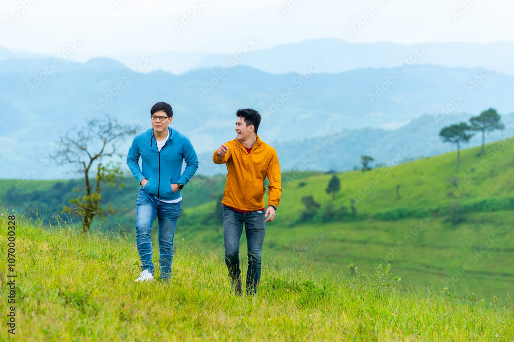 Two Asian man friends walking on mountain hill during camping together on the mountain. People enjoy outdoor active lifestyle travel nature hiking and camping at forest mountain on holiday vacation. Two Asian man friends walking on mountain hill during camping together on the mountain. People enjoy outdoor active lifestyle travel nature hiking and camping at forest mountain on holiday vacation.