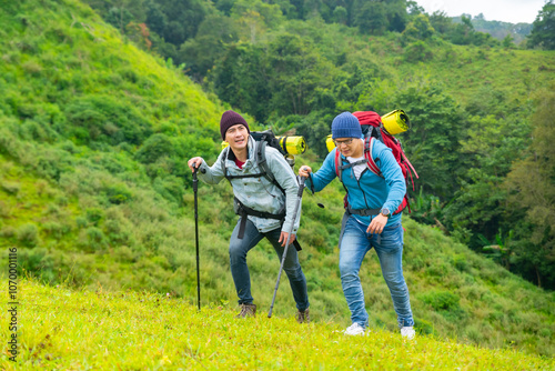 Asian men backpacker hiking on mountain hill in autumn. Healthy man traveler enjoy adventure outdoor active lifestyle hiking on nature trail mountain dirt road on holiday vacation. Ecotourism concept.