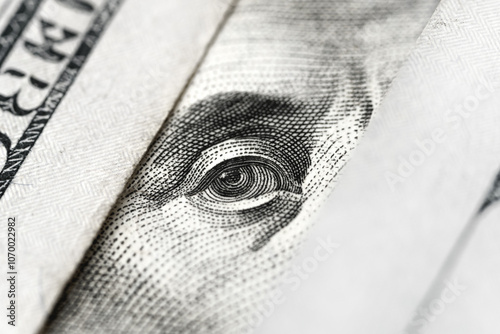 Macro photograph with close-up of Benjamin Franklin's eye on a U.S. one-hundred-dollar bill. Concept of mystery and focus on the observation or surveillance aspect, finance, scrutiny, and security. 