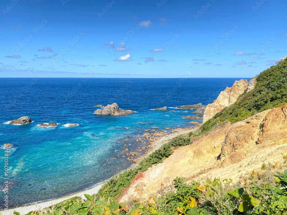 Scenic coastal view with blue ocean, cliffs, and lush greenery under a bright sky. Shimamui Coast Scenic coastal view with blue ocean, cliffs, and lush greenery under a bright sky. Shimamui Coast