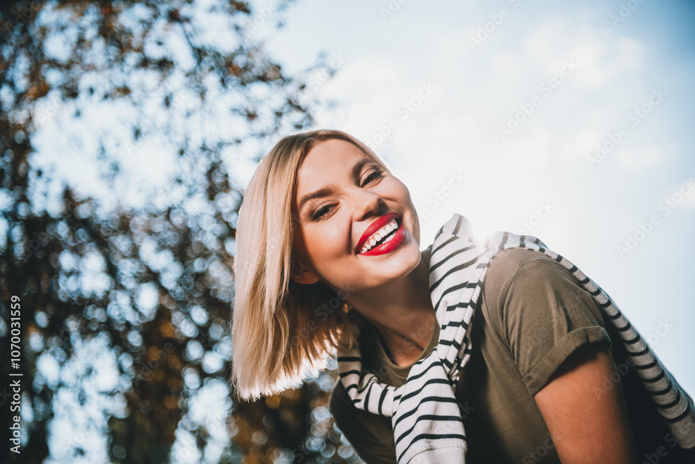 Photo of pretty young blonde woman dreamy smile wear khaki clothes tied shoulders sweater walk outside urban city park Photo of pretty young blonde woman dreamy smile wear khaki clothes tied shoulders sweater walk outside urban city park