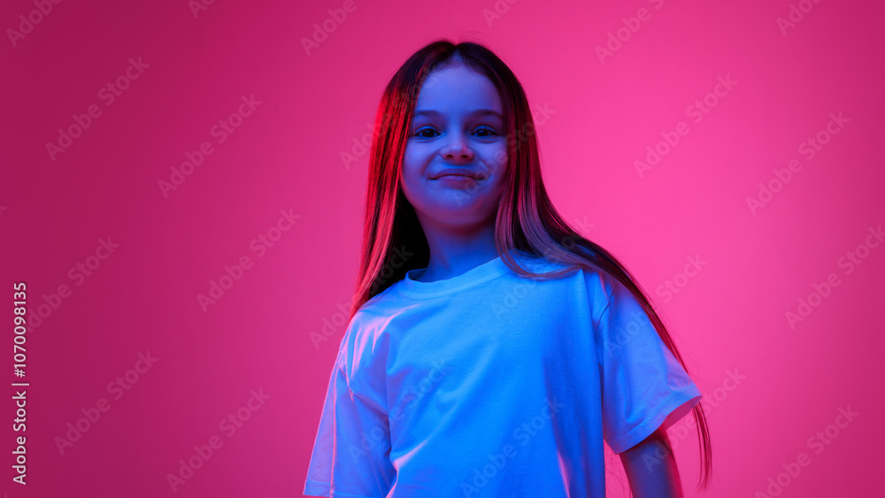 Fototapeta premium Young fashionista. Little girl, dressed white t-shirt smiling and looking at camera in neon light against vivid gradient background. Concept of childhood, lifestyle, expressions, trendy. Ad