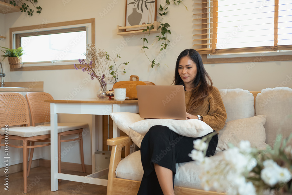 Attractive young woman working with laptop while sitting on couch Attractive young woman working with laptop while sitting on couch