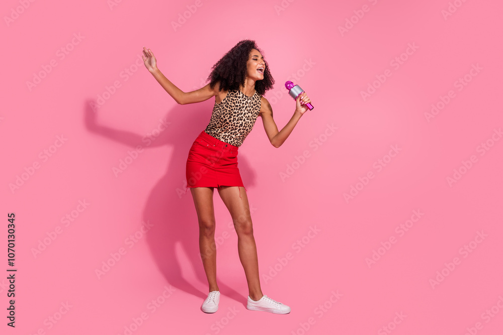 Full size photo of pretty young girl have fun sing karaoke wear trendy leopard print outfit isolated on pink color background Full size photo of pretty young girl have fun sing karaoke wear trendy leopard print outfit isolated on pink color background