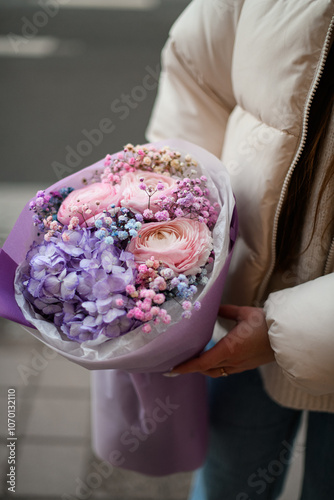 Focus on a bouquet of purple hydrangeas, peonies and gypsophila in purple wrapping paper photo