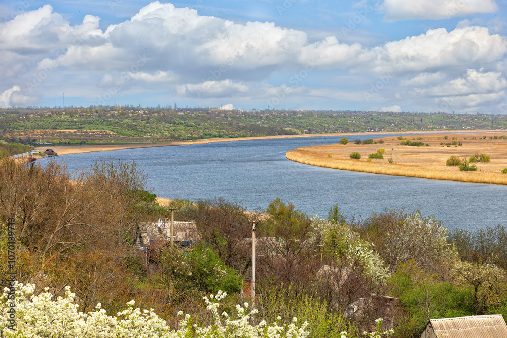 A tranquil river view winding through lush landscapes under a bright blue sky in springtime