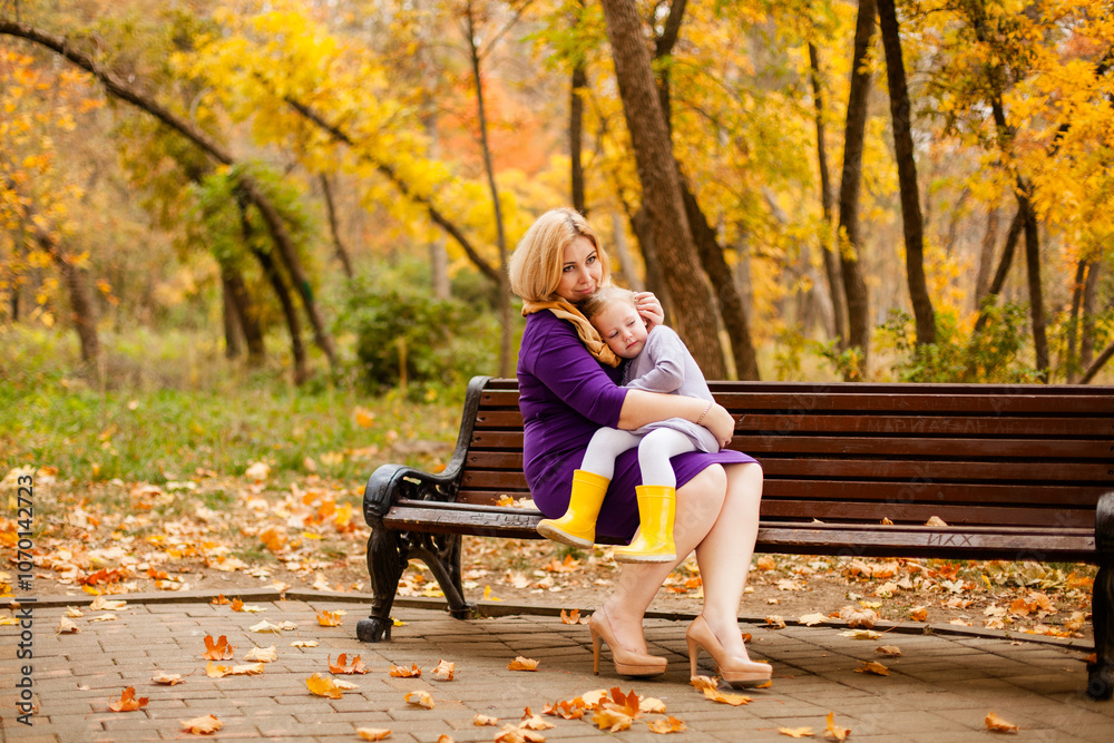 Loving mother in purple dress hugging her sad daughter on park bench Loving mother in purple dress hugging her sad daughter on park bench