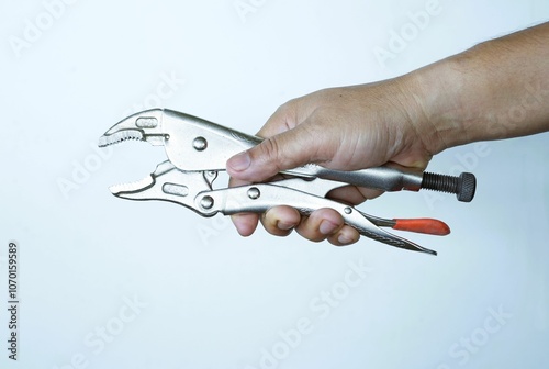 A human hand holds steel pliers, a common tool for pinching and holding. photo