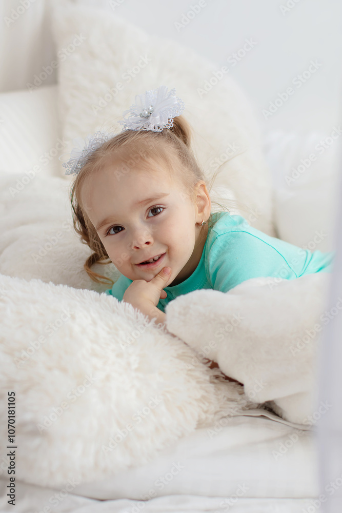 Little girl in a green shirt on white pillows. Little girl in a green shirt on white pillows.