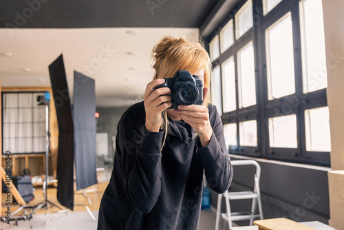 Photographer taking photos in professional studio with lighting equipment photo