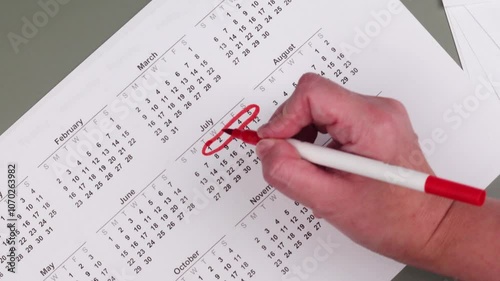 Hand fills in a large wall calendar, counting down the days and marking 'Vacation' - the concept of planning and anticipating a vacation or holiday break.
