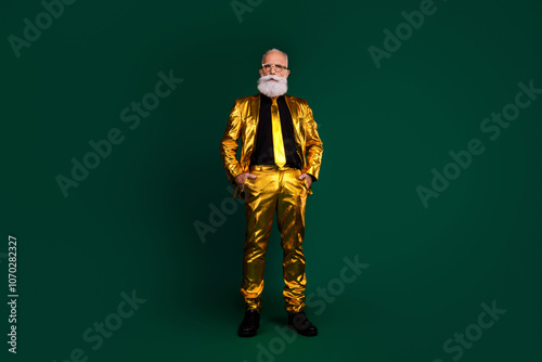 Charismatic gentleman in glowing golden suit with beard posing elegantly against green background.