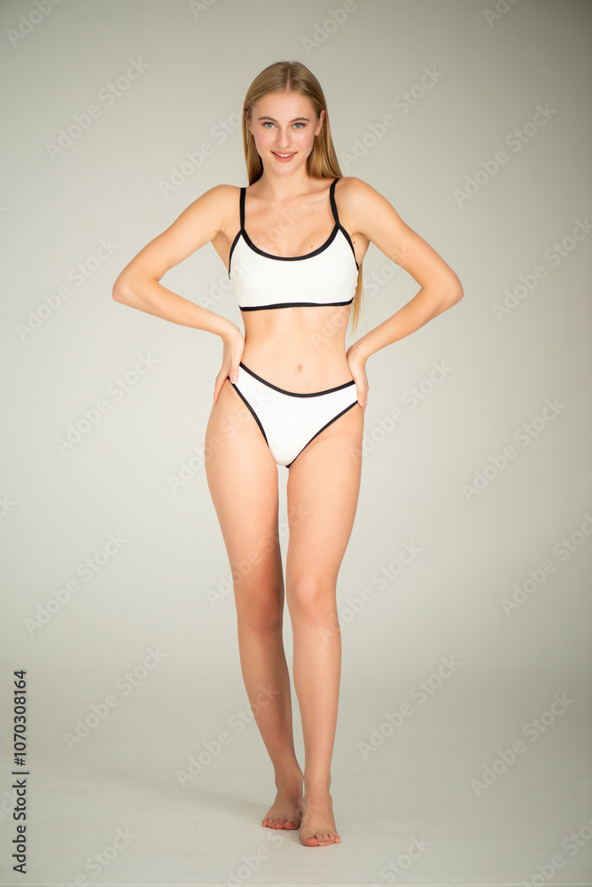 Fototapeta premium Summer, body and portrait of woman in studio with confidence for fashion and swimwear. Model girl, happiness and bikini for tropical holiday and relax with aesthetics and glow by white background