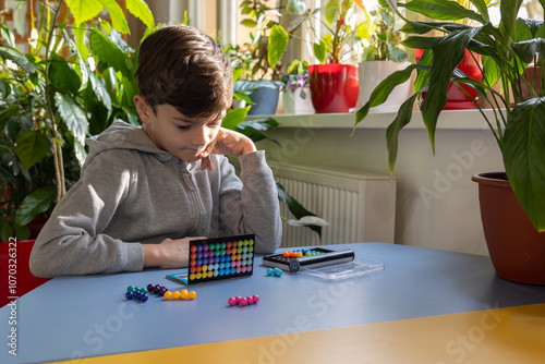 young boy engaged in a logical board game, fostering child development, intellectual growth, and mental well-being in a supportive, inclusive environment. Focus on psychology, therapy, and early lear
