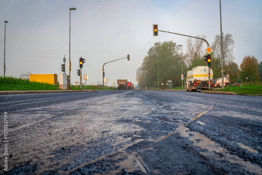 Old Asphalt Prepared for New Layer with Traffic Lights and Trucks at Construction Site Old Asphalt Prepared for New Layer with Traffic Lights and Trucks at Construction Site
