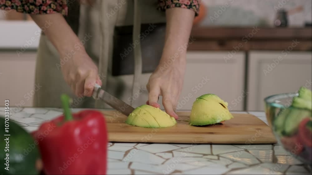 Chef is slicing an avocado in half on a cutting board in preparation for a meal Chef is slicing an avocado in half on a cutting board in preparation for a meal
