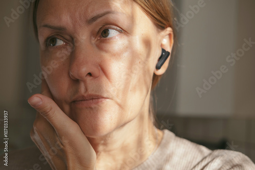 Mature woman in headphones enjoying music at home. Caucasian middle-aged freelancer listening to podcast radio e-book playlist online in mobile application. 