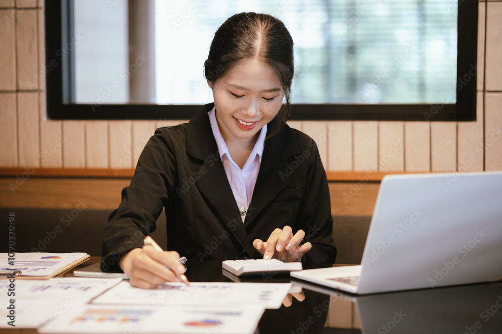 Young asian businesswoman analyzing financial chart using digital tablet and calculator in office