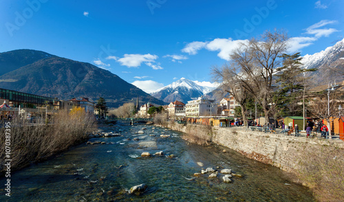 Photography Tourists walking along the passer river in merano, italy, on a sunny winter day
