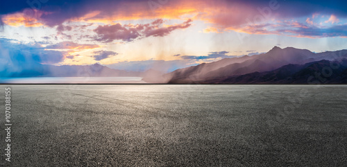 Asphalt road square and lake with mountain nature landscape at sunset. It's raining in the distance. Car advertising background.