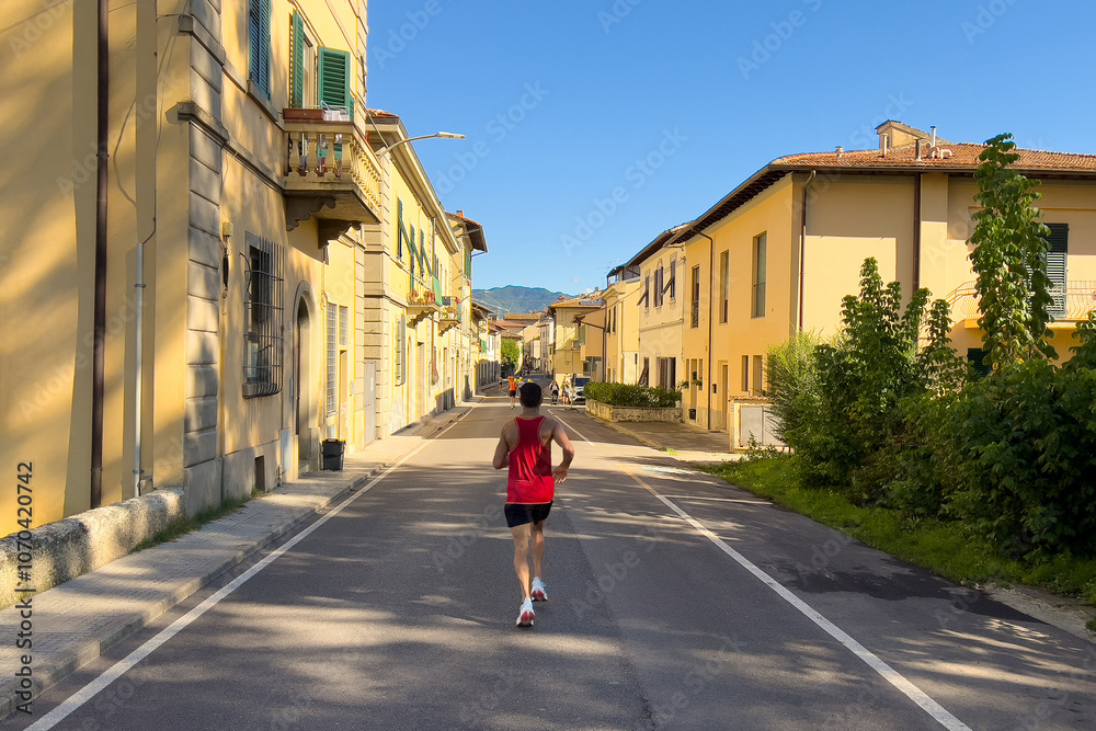 rear view runner running down street of Italian city half marathon race rear view runner running down street of Italian city half marathon race