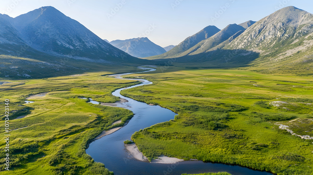 Fototapeta premium Aerial view of a winding river flowing through a lush valley surrounded by majestic mountains.