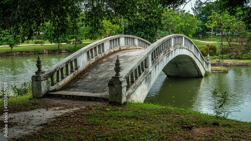 An arched stone bridge over a pond in a park.