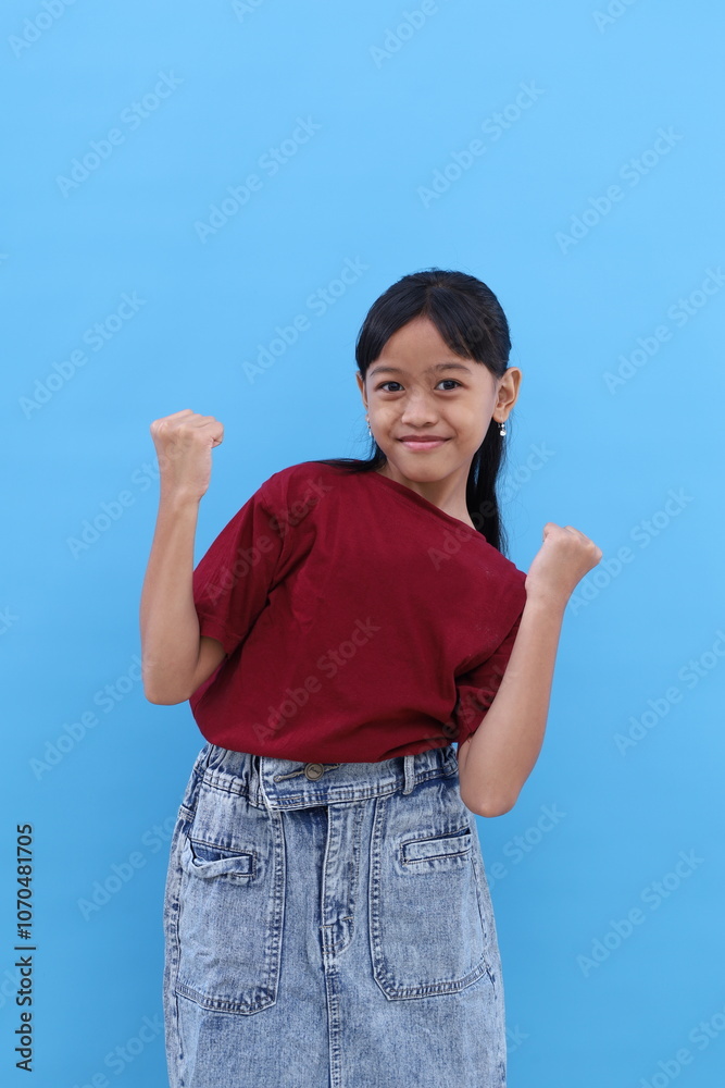 Cheerful asian little girl in red standing while dancing. Isolated on blue with copyspace Cheerful asian little girl in red standing while dancing. Isolated on blue with copyspace