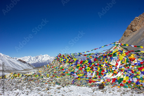 Thorong la pass with many colorful buddhist prayer flags in the background snowy himalayan ridge photo