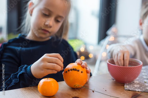 Children making Christmas pomander balls with oranges and cloves for fragnant festive decorations photo