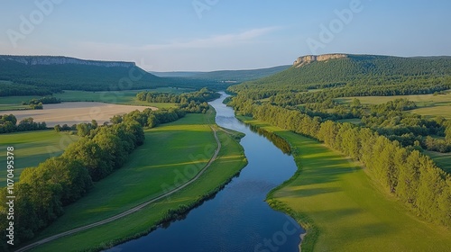 Aerial view of a winding river flowing through a valley with green fields and trees.