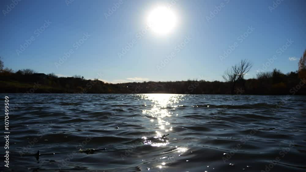 View on lake with waves at sunny summer day. Calm scenery of pond with sunlight at background. Beautiful nature landscape. Concept of tranquility scene. Slow motion View on lake with waves at sunny summer day. Calm scenery of pond with sunlight at background. Beautiful nature landscape. Concept of tranquility scene. Slow motion
