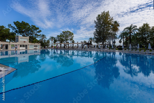 Obraz na płótnie Magnificent view, swimming pool with blue sky with clouds. Holiday hotel in Antalya. Great relaxation and peaceful atmosphere, palm trees, sun loungers reflections. w salonie