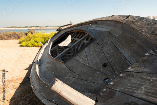 Old abandoned dhow boats standing in row on the shore of bay in UAE. Arabic traditional wooden boat. Old wooden boats left on land near the shore. Boats are badly worn and covered with rust photo