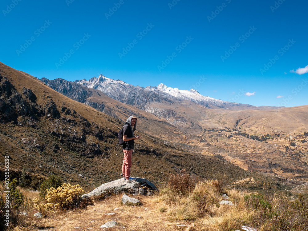 Young White Man Stands on a Rock Admiring the Mountains on his Way to the Churup Lagoon in Ancash, Peru