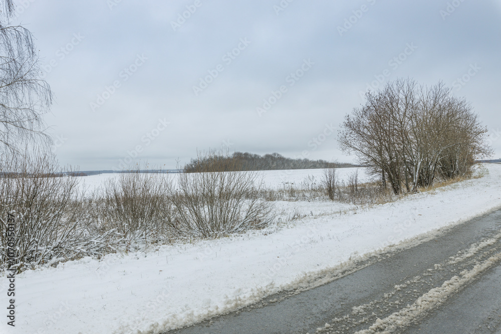 A snowy road with a tree line in the background