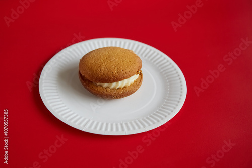 Pumpkin pie with cream on a white disposable plate against a red background, autumn sweet dessert, pumpkin dessert.