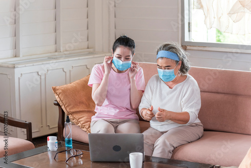 Obraz na płótnie Asian young woman teach older mother, how to wear face mask in living room with carefully. family concept w salonie