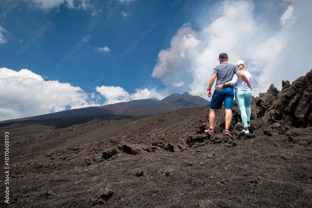 Naklejka premium Couple tourist getting lost in Mount Etna, active stratovolcano in Catania, Sicily region. It is one of the tallest active volcano in Europe. Travel and sightseeing journey concep